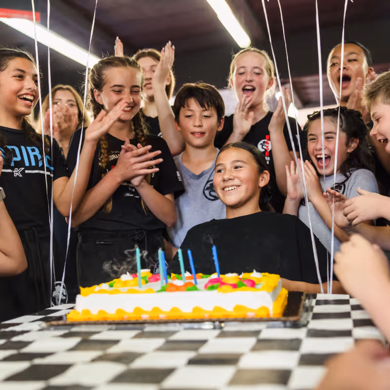 A smiling young girl is attending a karate-themed birthday party.