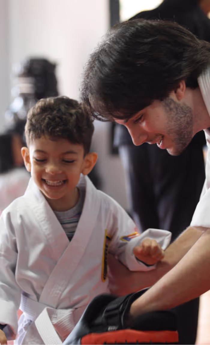 A USSD Instructor is coaching a small giggling child during karate class.