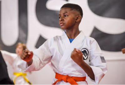 A young boy in a guard position participating in a kids karate class
