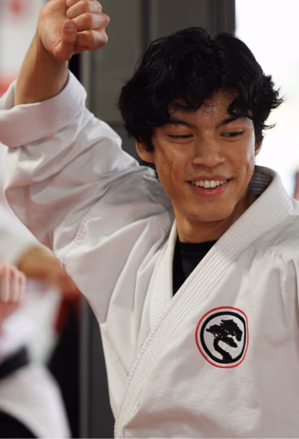 An adult karate student smiles while he participates in an adult karate class.