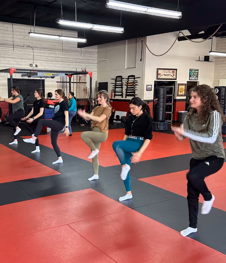 Participants in a women's self defense class are warming up with some calisthenics.