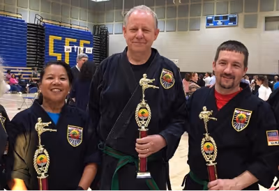 Adults Smile as they hold their karate tournament awards.