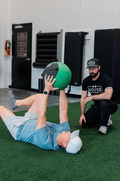 Coach supporting an adult client during a medicine ball exercise