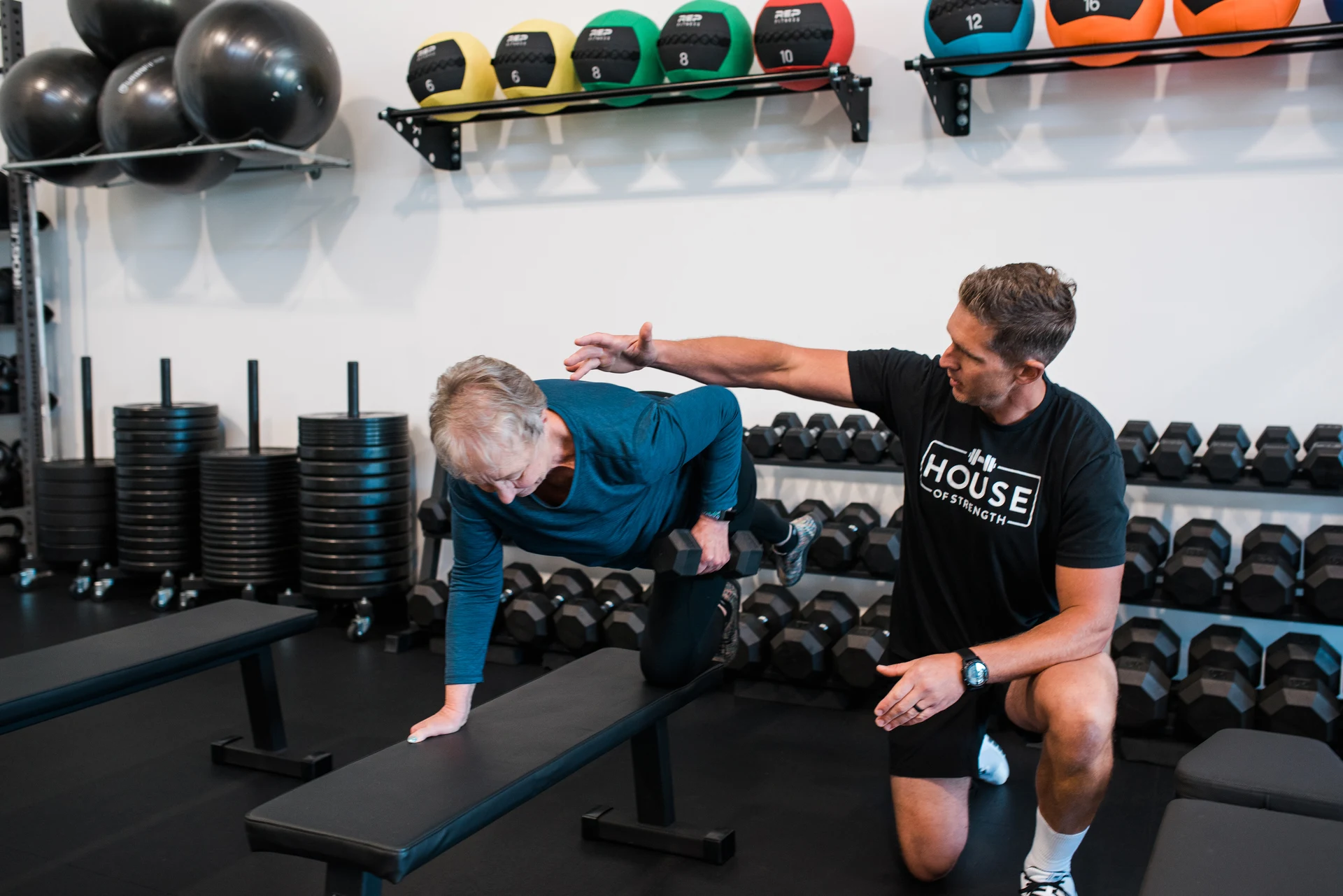 House of Strength coach guiding an adult client through a strength exercise at the Windsor training facility.