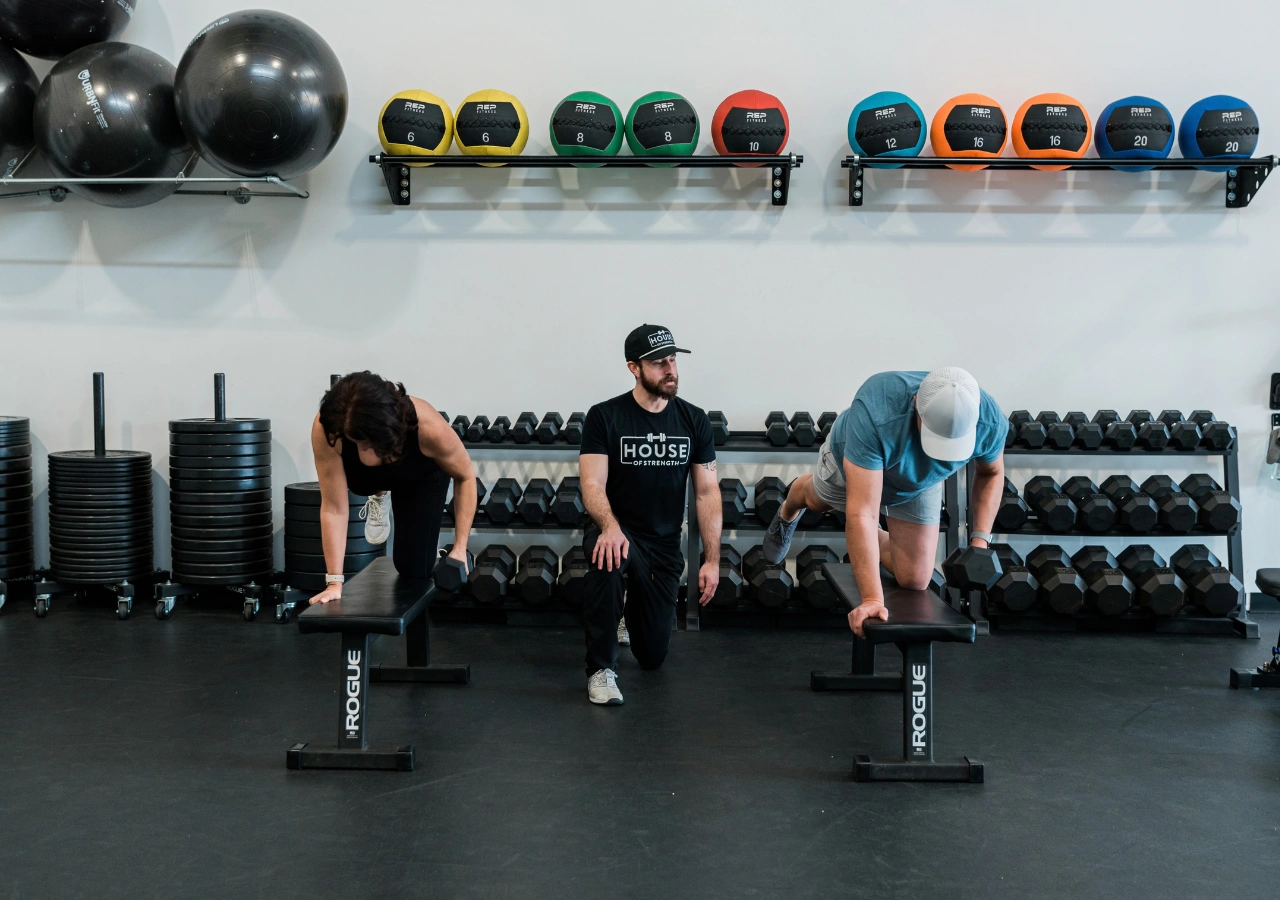 House of Strength coach guiding an adult client through a strength exercise at the Windsor training facility.