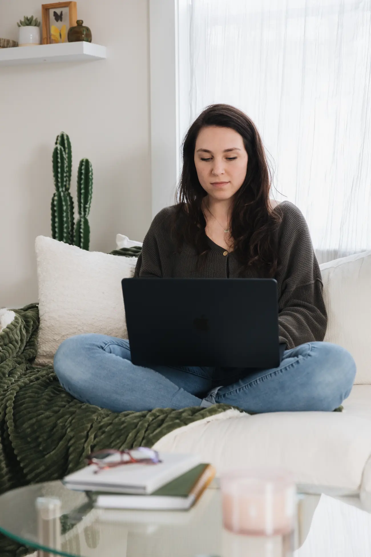 Small business bookkeeper sitting on a couch on her laptop working on her monthly bookkeeping clients and updating clients on their finances