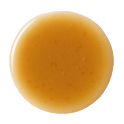 Light brown vegetable broth with a smooth, slightly cloudy texture, pooled in a round shape on a white background