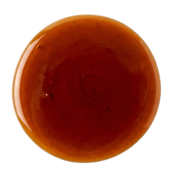 Burnt Sugar Syrup as a glossy, dark amber liquid with a thick, smooth texture pooled in a circular shape