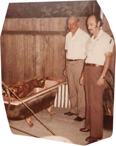 an old photo of two men roasting a pig