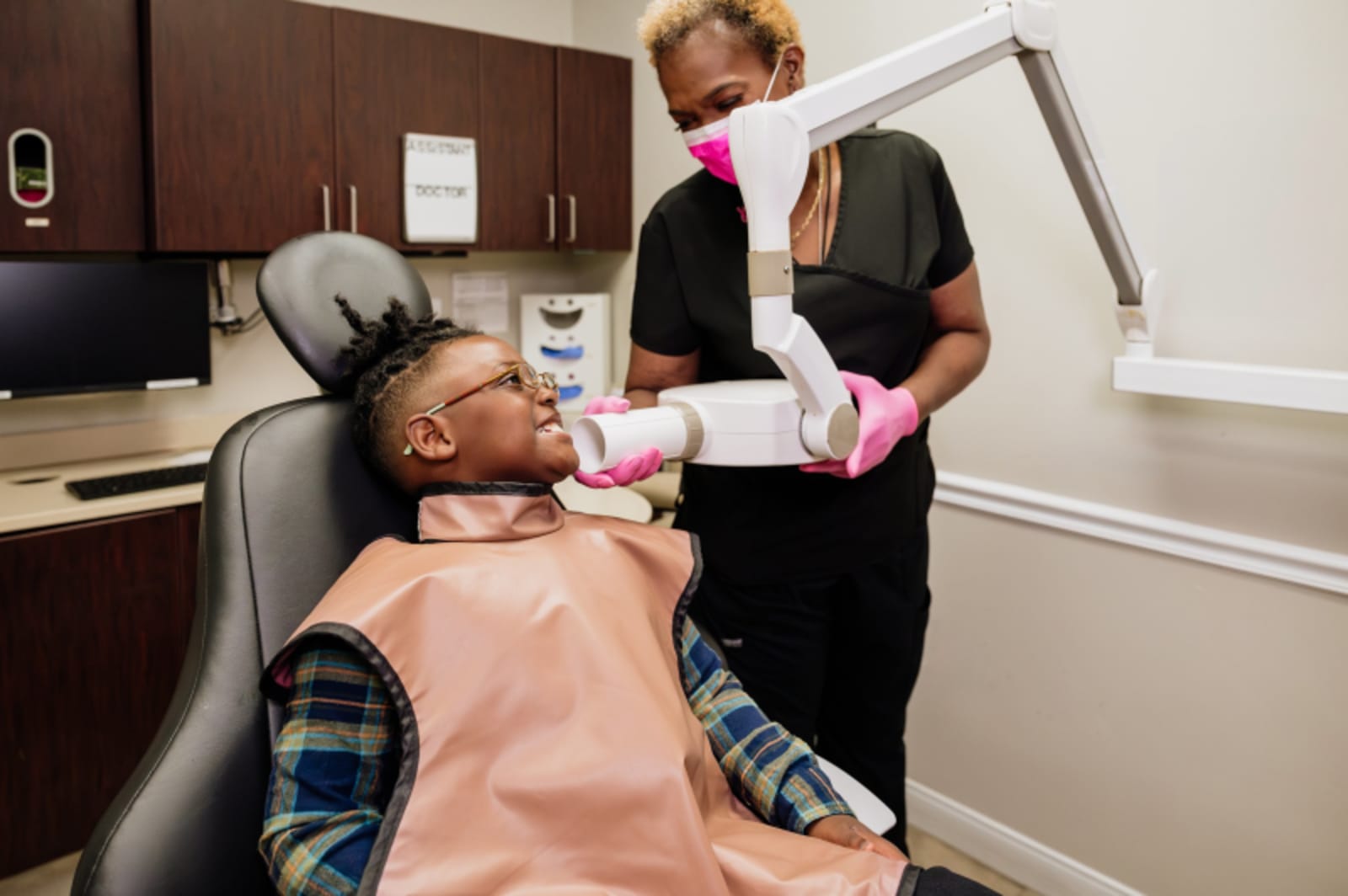 Pediatric dentist examining young patient in dental chair during oral evaluation