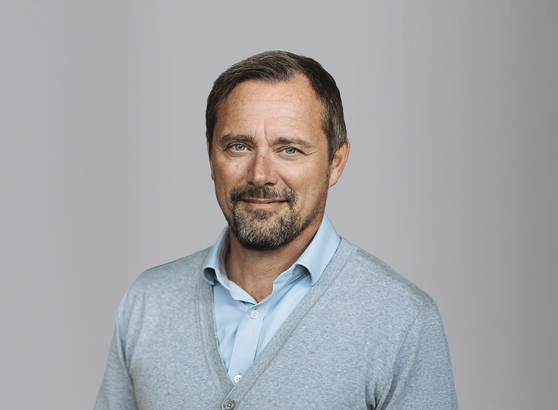 Niclas, Midsona executive in grey cardigan and light blue shirt, professional headshot against grey background