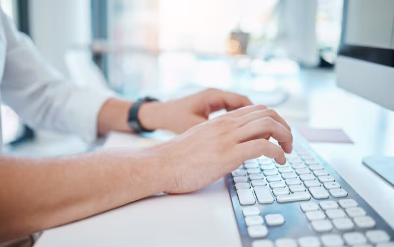 Close-up of hands typing on a keyboard, highlighting the urgency for NetSuite optimization assistance.