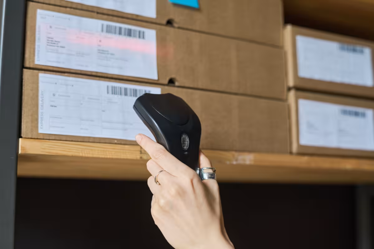 Individual using a barcode scanner near a shelf, highlighting NetSuite's e-commerce inventory management solutions.