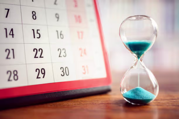 Hourglass on a desk beside a calendar, symbolizing time management for month-end close in NetSuite.