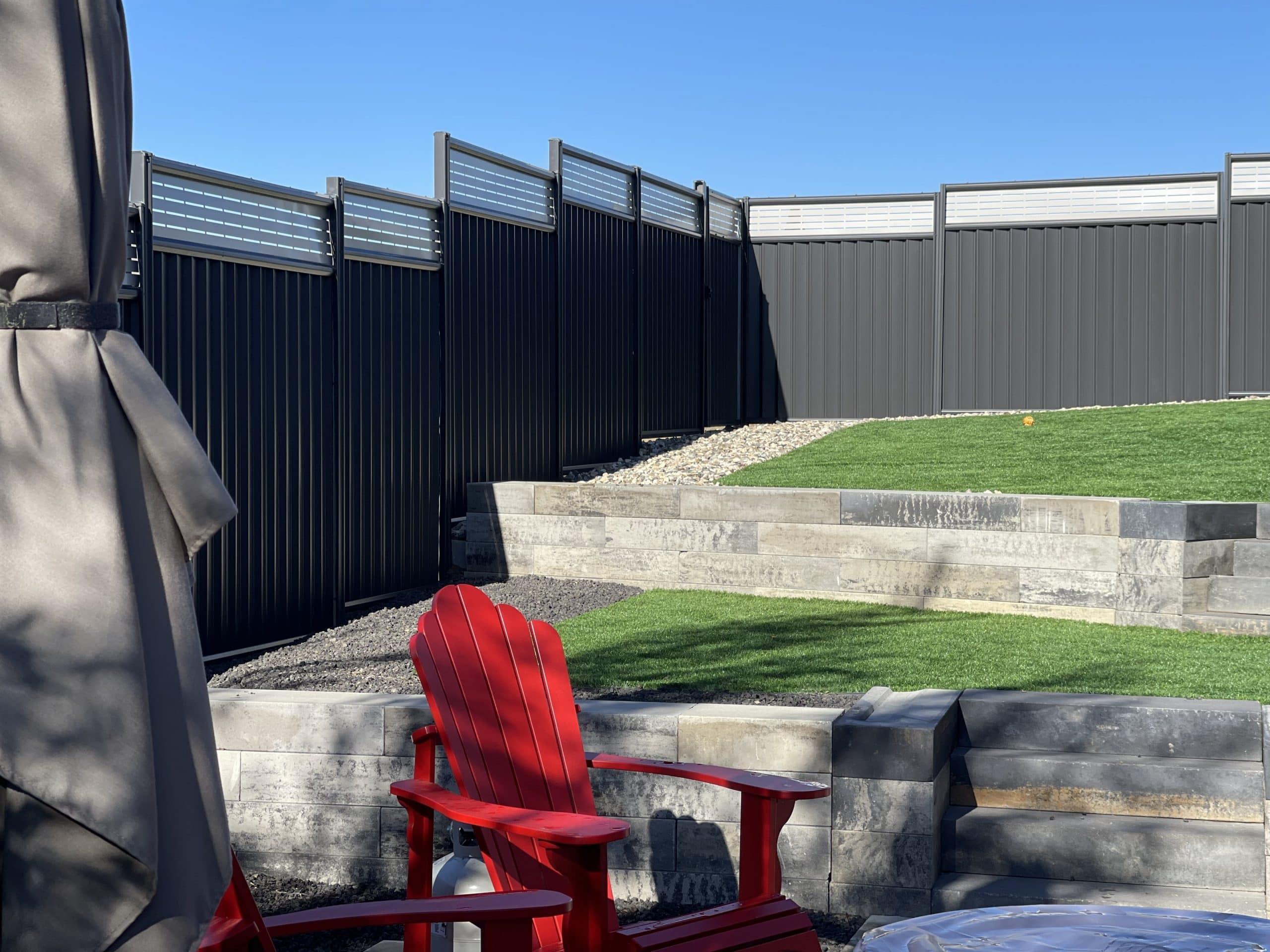 Backyard with sleek dark gray Colorbond fence featuring horizontal slat panels on top