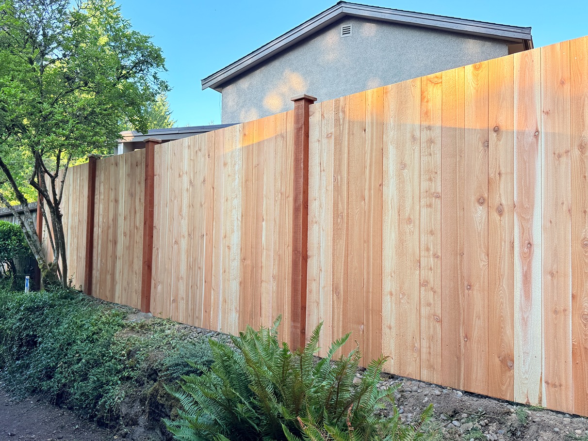 Front view of an estate fence featuring vertical cedar boards with a flat top and exposed posts
