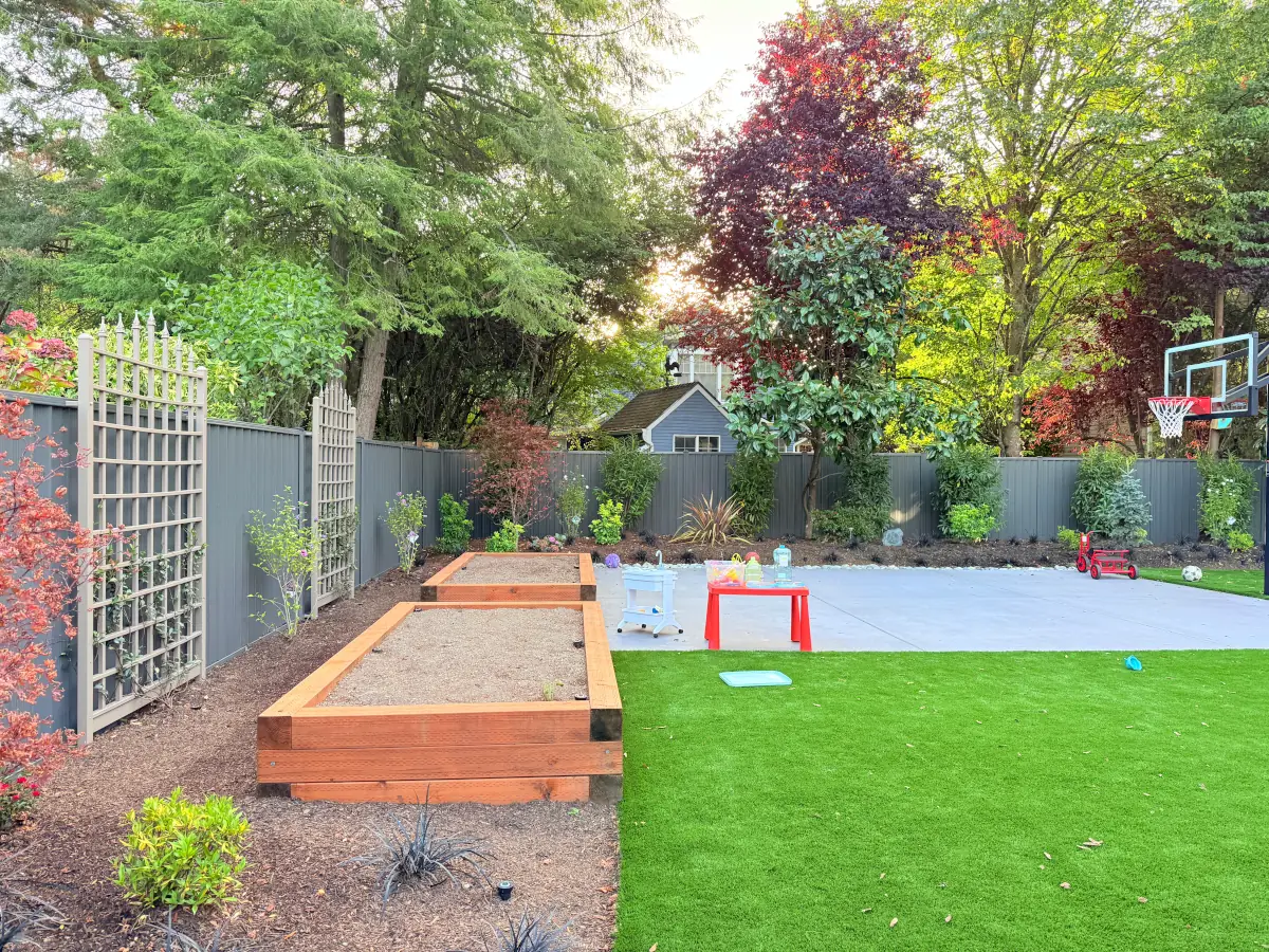 ColorMax steel privacy fence installed in a Bellevue backyard with raised garden beds and a sports court.”