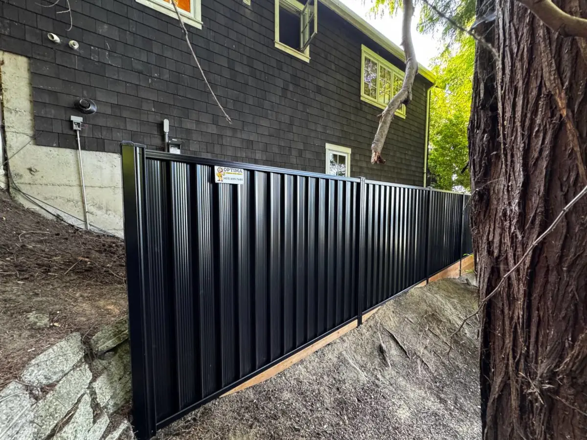 Durable ColorMax steel fencing in black installed near trees and hot tub area.
