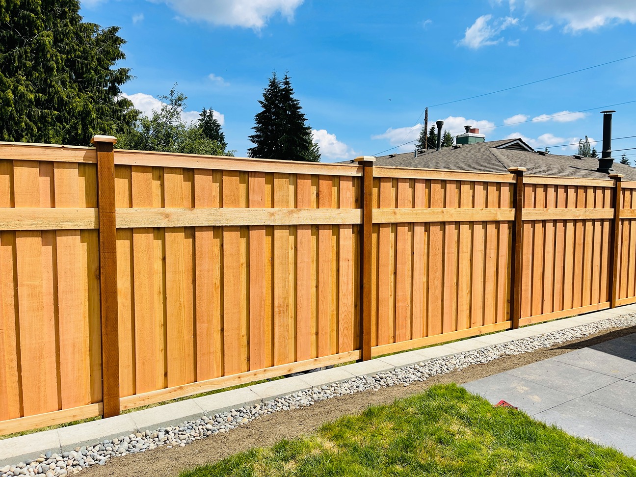 Tall custom cedar fence with board-on-board design and decorative top trim installed along a residential property line
