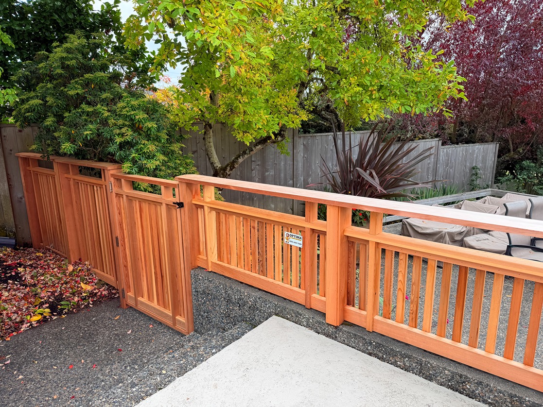 Custom cedar fence with matching gate and open-top slat design, built on a raised landscape area in a residential backyard
