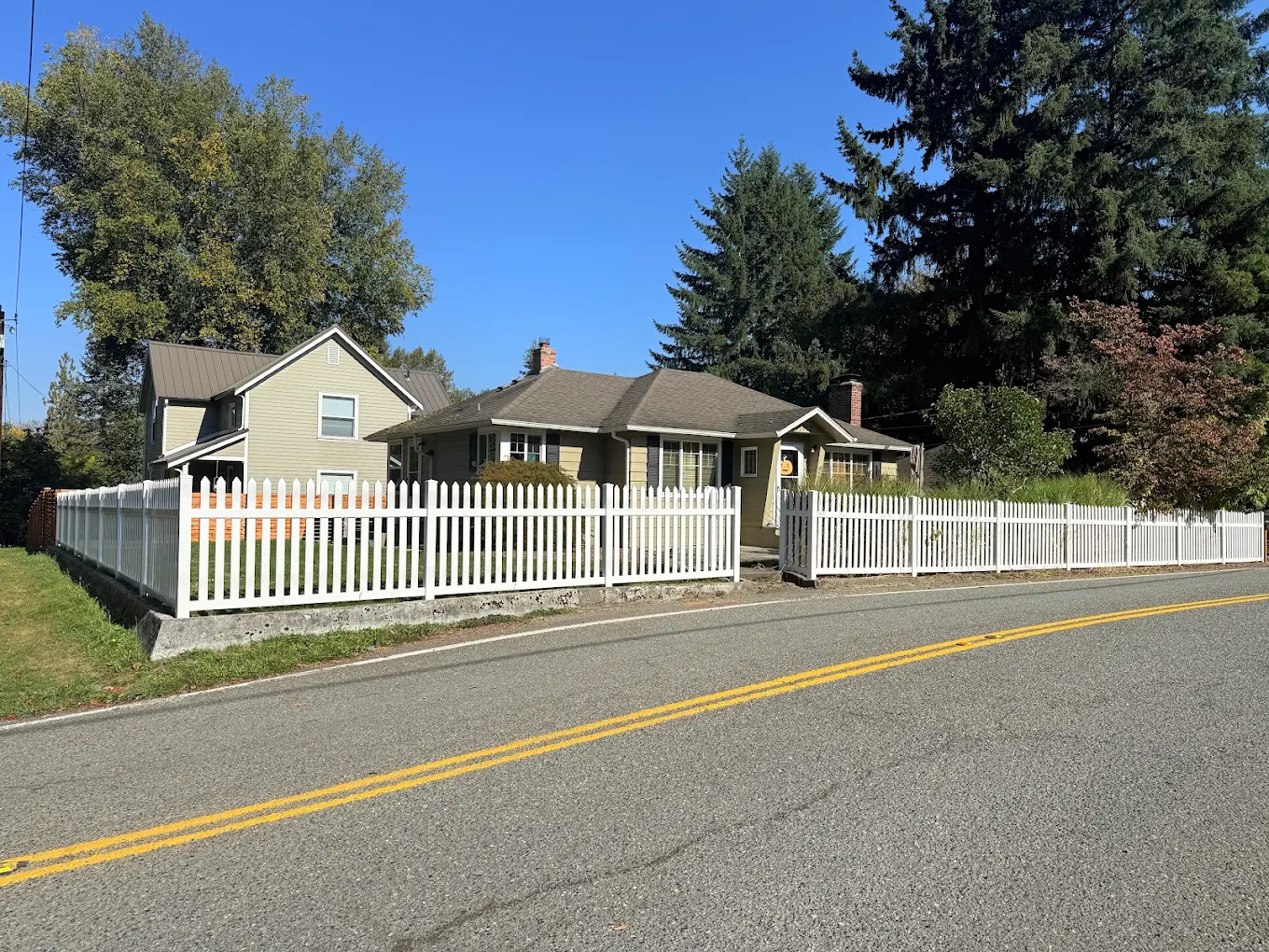 White vinyl picket fence installed along a sidewalk in a residential Bellevue neighborhood by Optima Fence and Deck