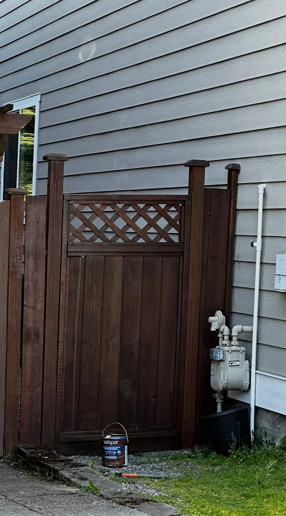 Dark brown walnut-toned faux wood vinyl fence with realistic grain texture in a residential yard