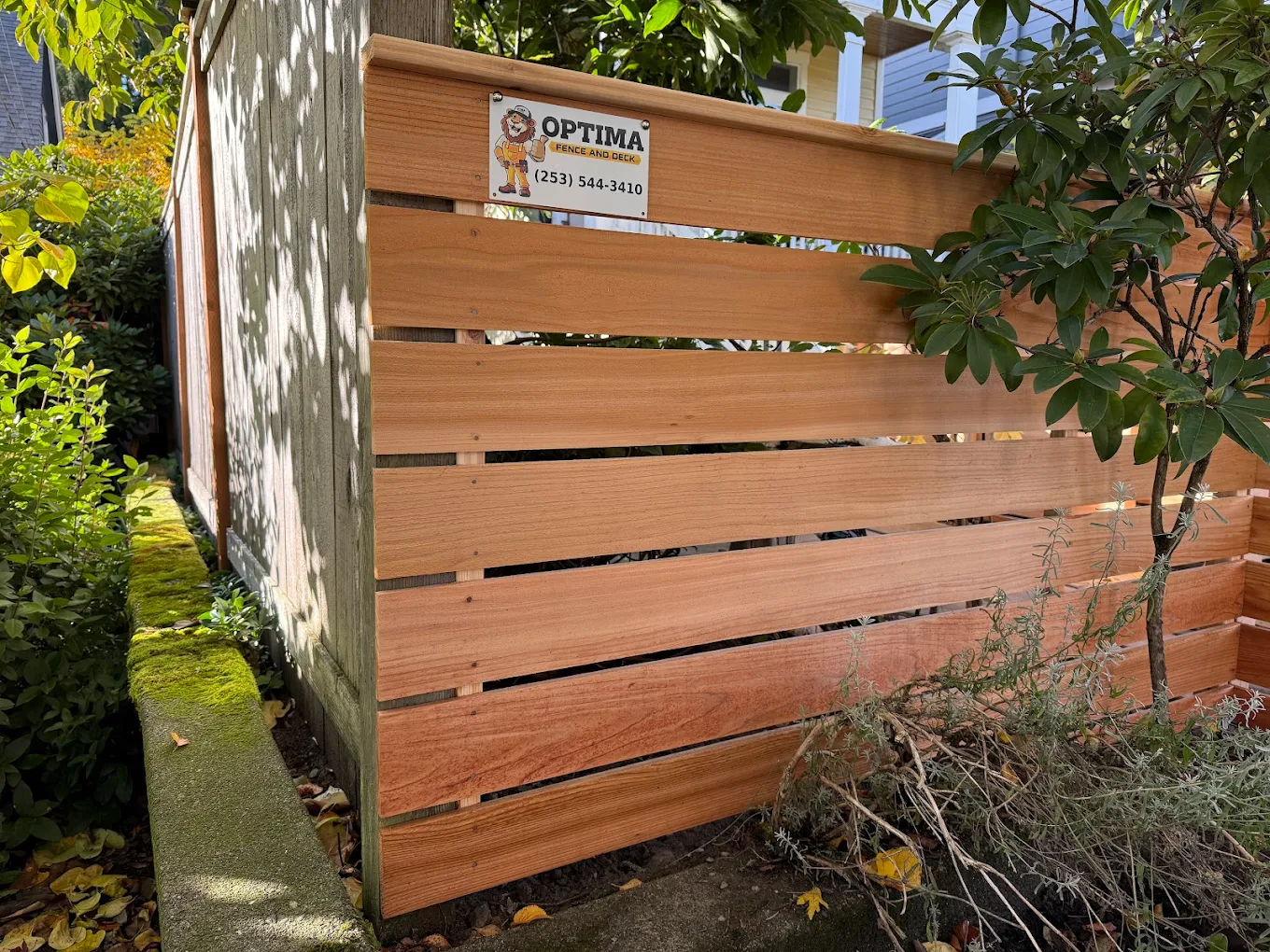 Cedar-toned faux wood vinyl fence with realistic wood grain texture installed along a residential property in Bellevue