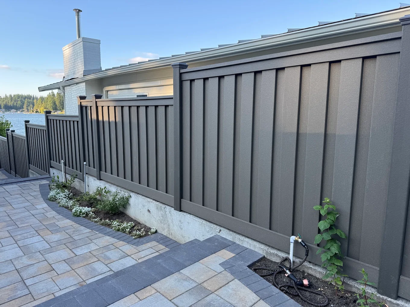 Dark gray composite fence near a faucet and shrubs in Bellevue