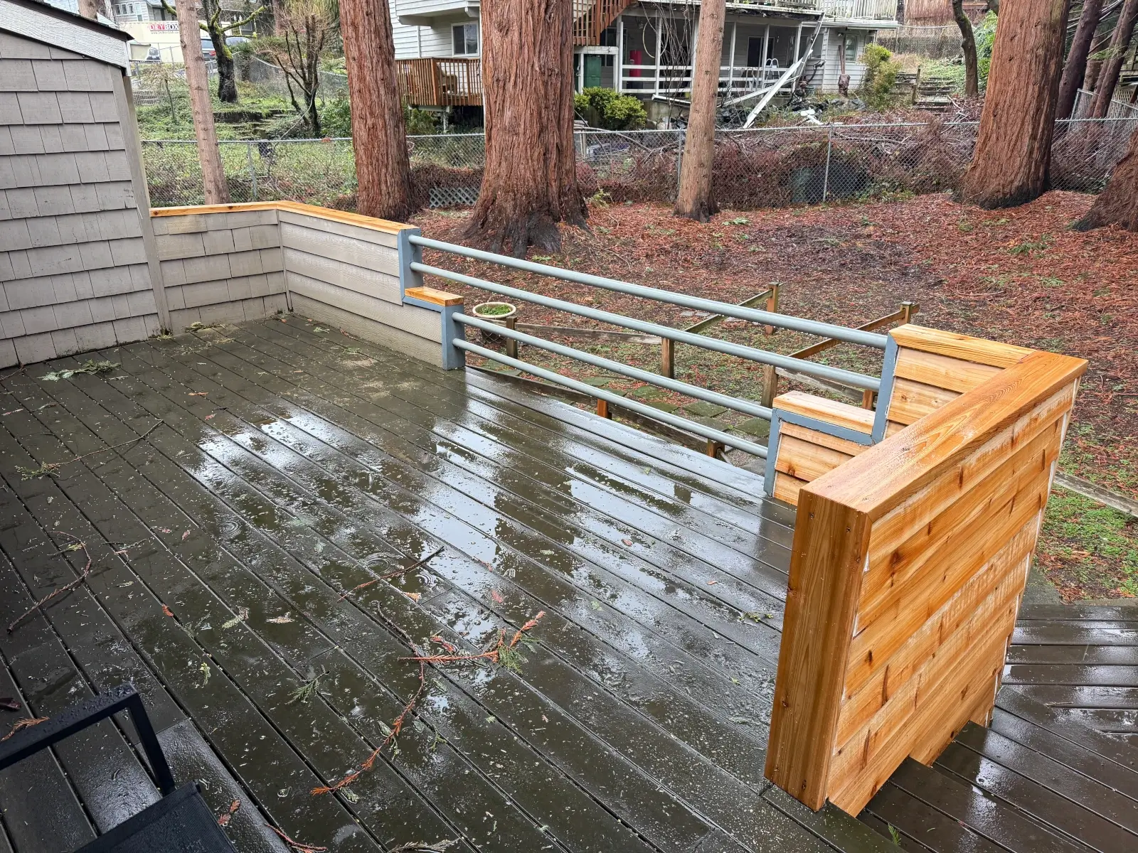 Newly repaired wooden deck featuring smooth cedar railings and fresh stain finish, with clean gray composite decking