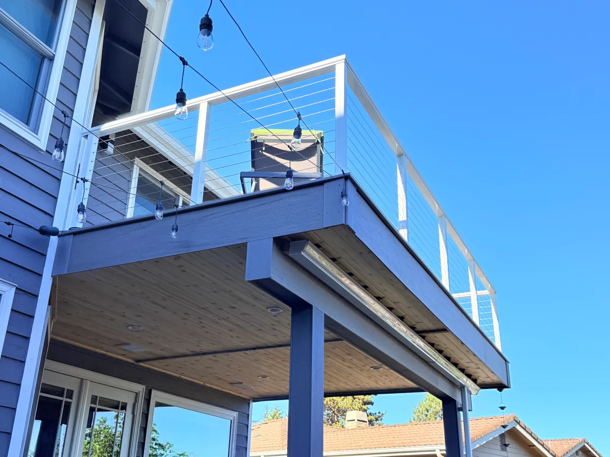 Close-up of a custom two-story composite deck in Tacoma with aluminum cable railing and integrated lighting