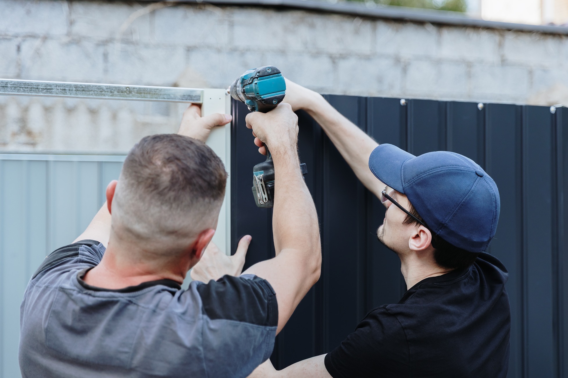 Construction Workers Assembling Panel with Drill Outdoors