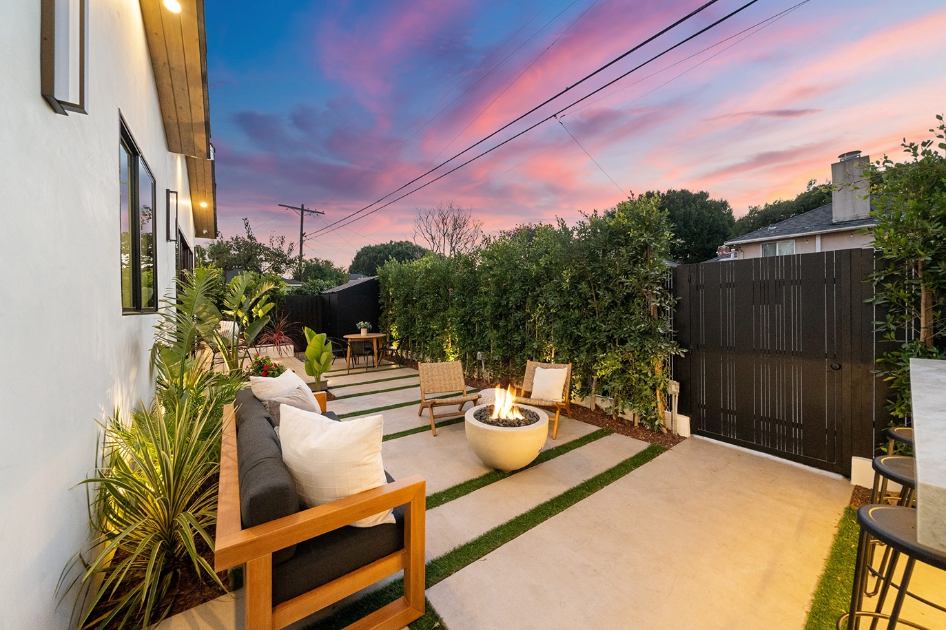 Modern backyard patio with fire pit, privacy fence, and outdoor lighting showing how to increase home value with outdoor space upgrades