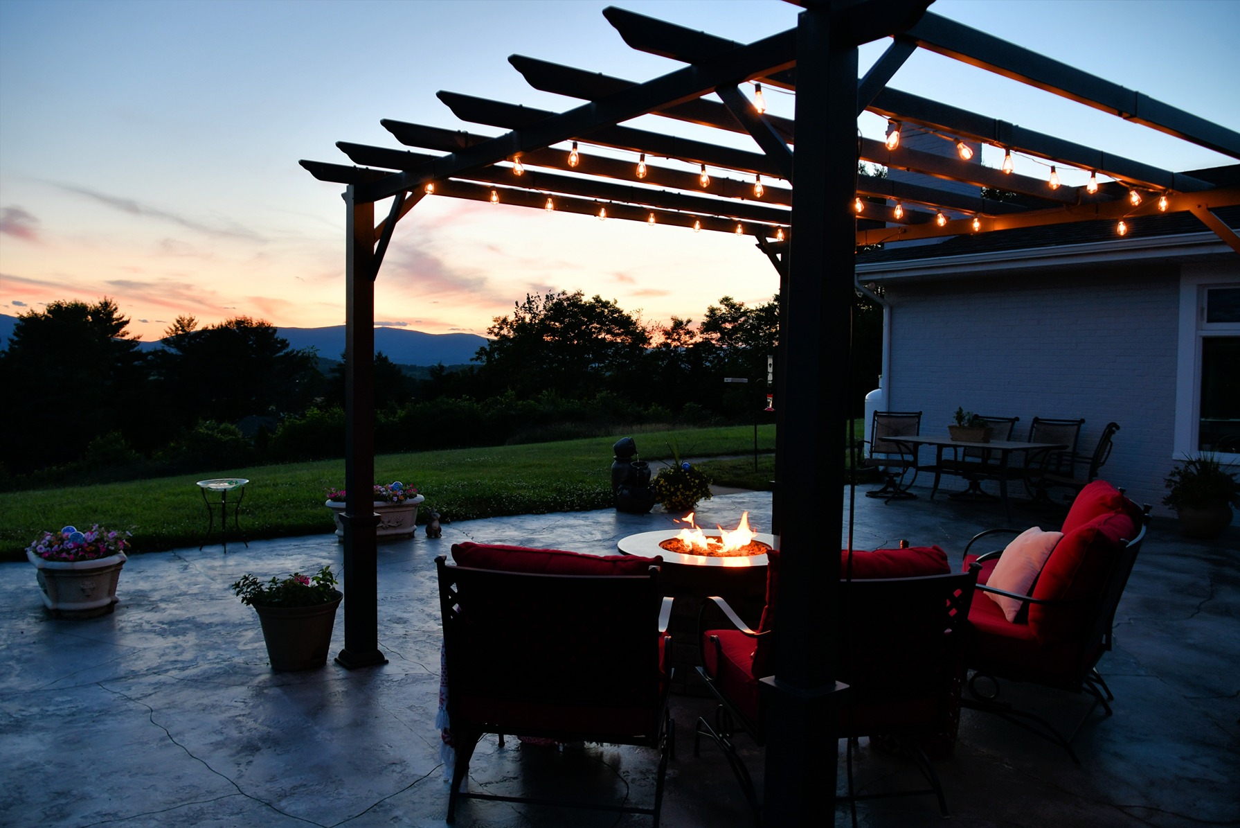 Modern backyard pergola with string lights and outdoor dining area at dusk