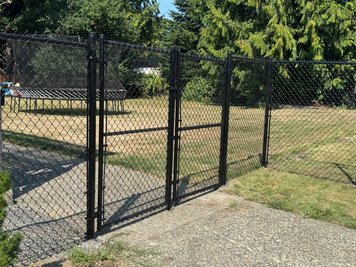 Black vinyl-coated chain link fence with gate securing a play area in Bellevue
