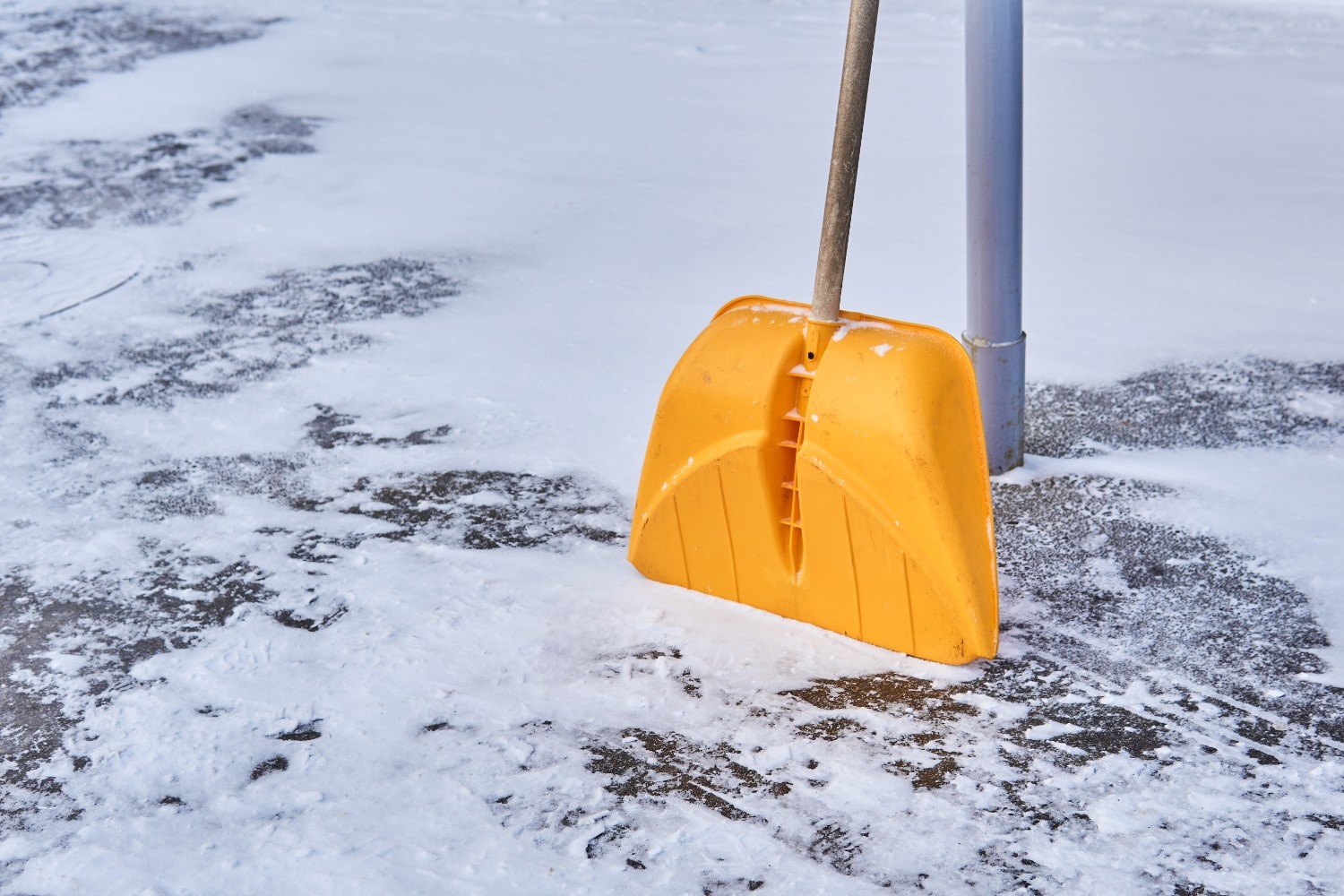 Plastic snow shovel clearing light snow from a composite deck surface in western Washington