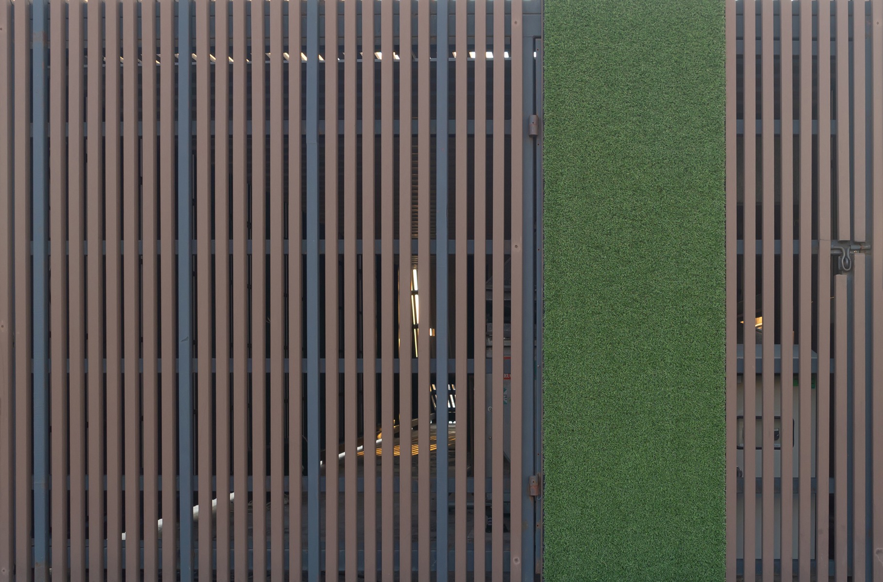 WPC composite fence panel with vertical slat design next to a green turf strip on a residential property