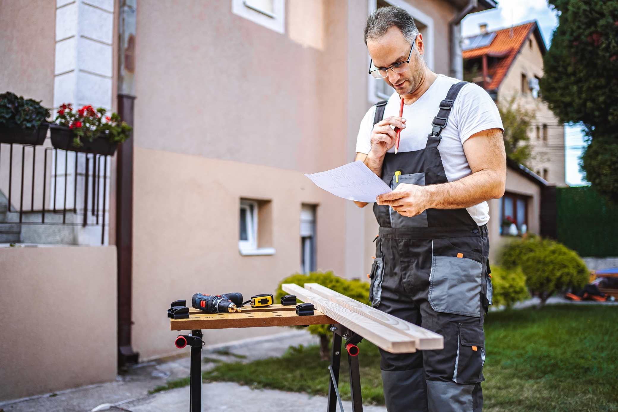 Contractor reviewing a printed site plan beside a property stake on a Seattle lot