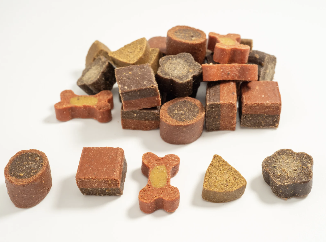 alt text: dog with treats on a table looking up