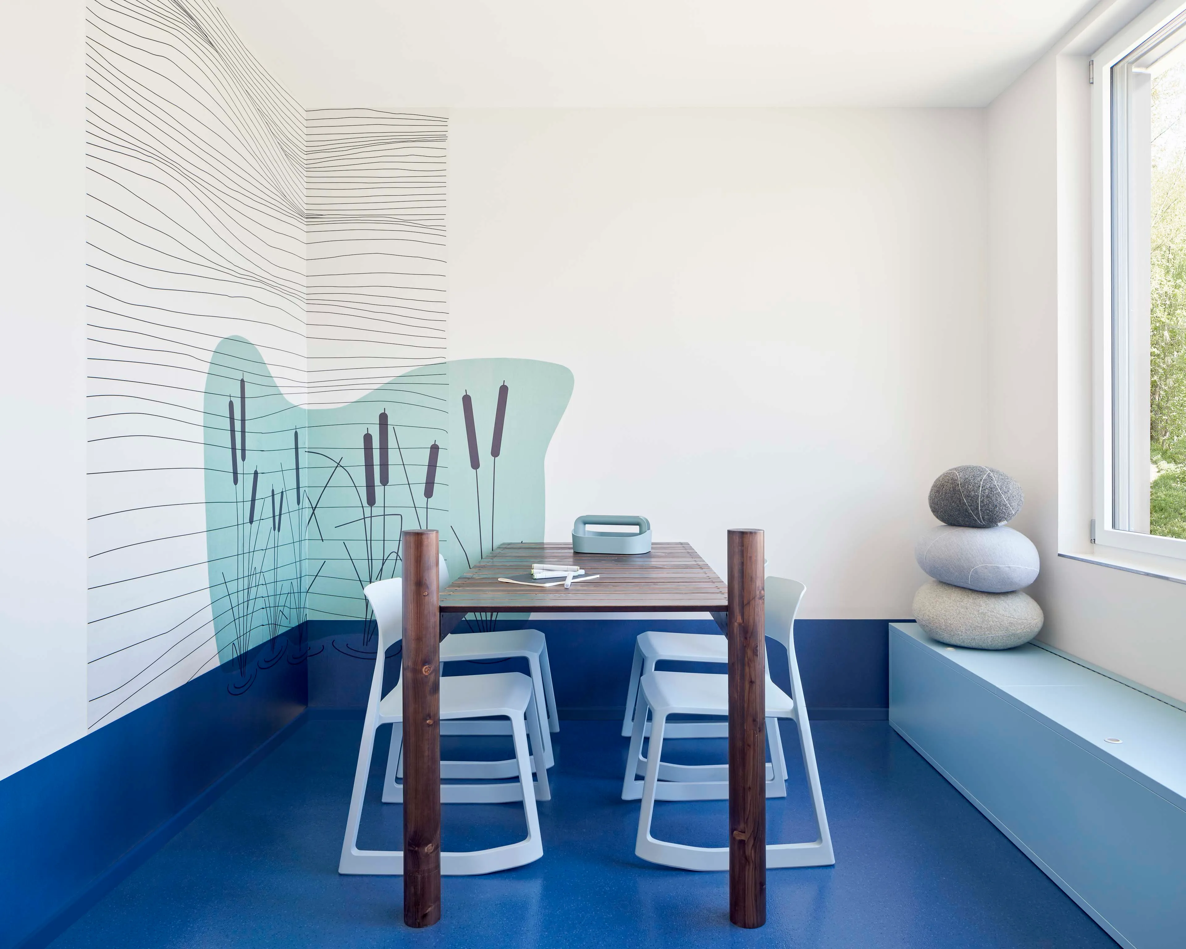 Moderner Raum mit einem Holztisch, vier weißen Stühlen, blauer Boden, Fenster und Wandkunst mit Schilfdesign.