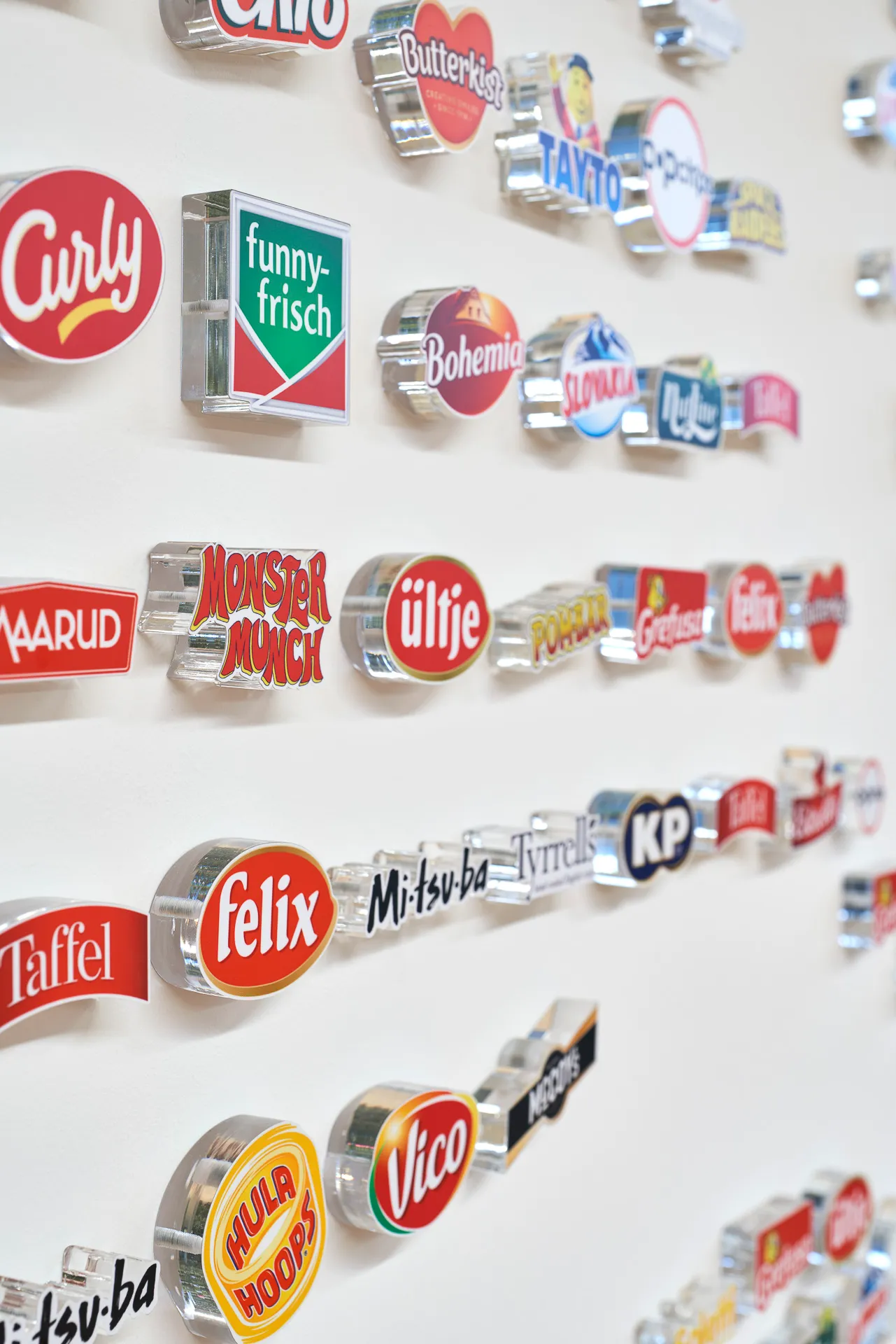 Wand mit 3D-Logos verschiedener Snack- und Lebensmittelmarken wie Felix, Hula Hoops, Monster Munch und mehr.