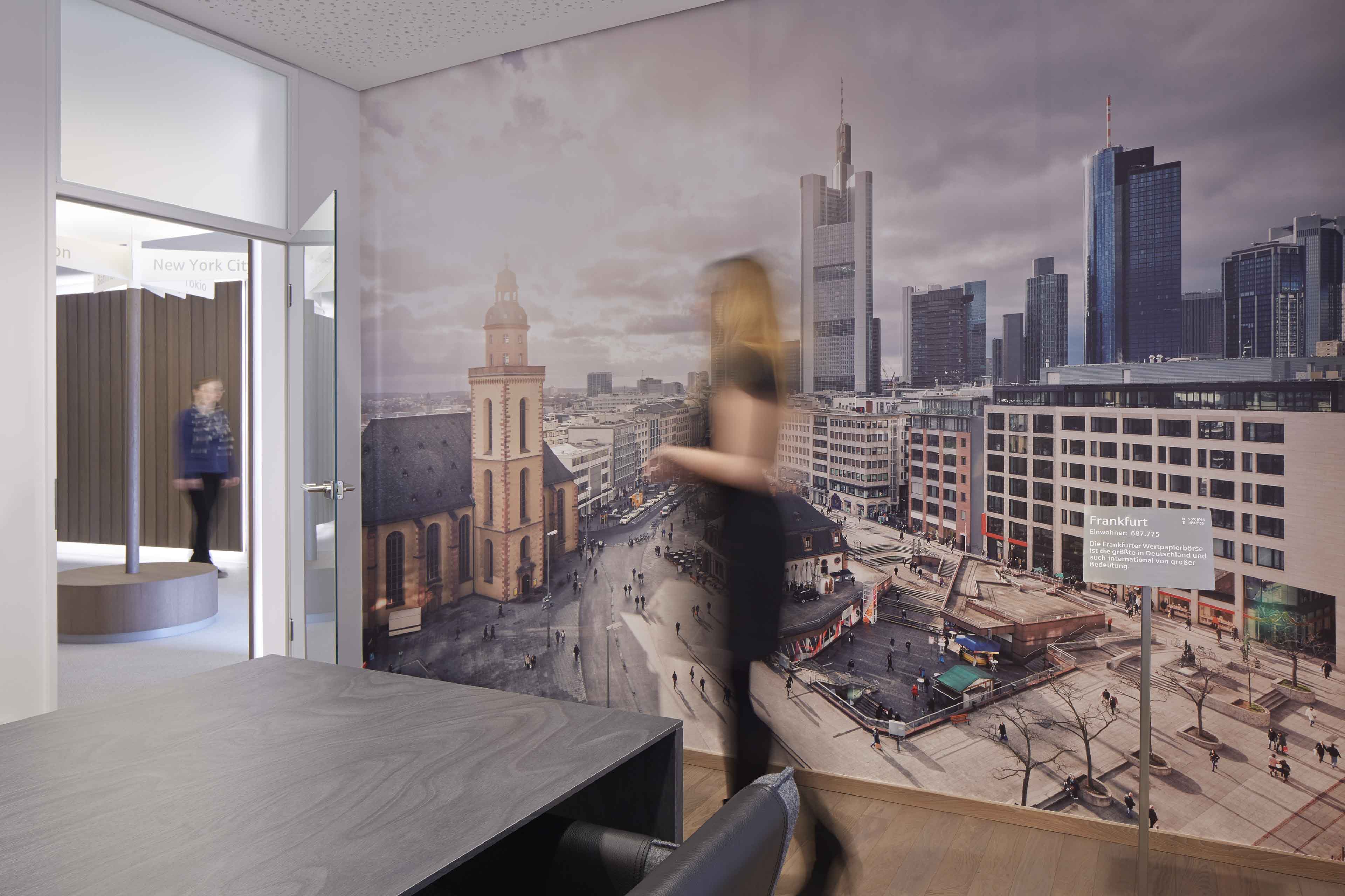 Innenraum mit großem Wandbild der Frankfurter Skyline und zwei verschwommenen Personen in Bewegung.