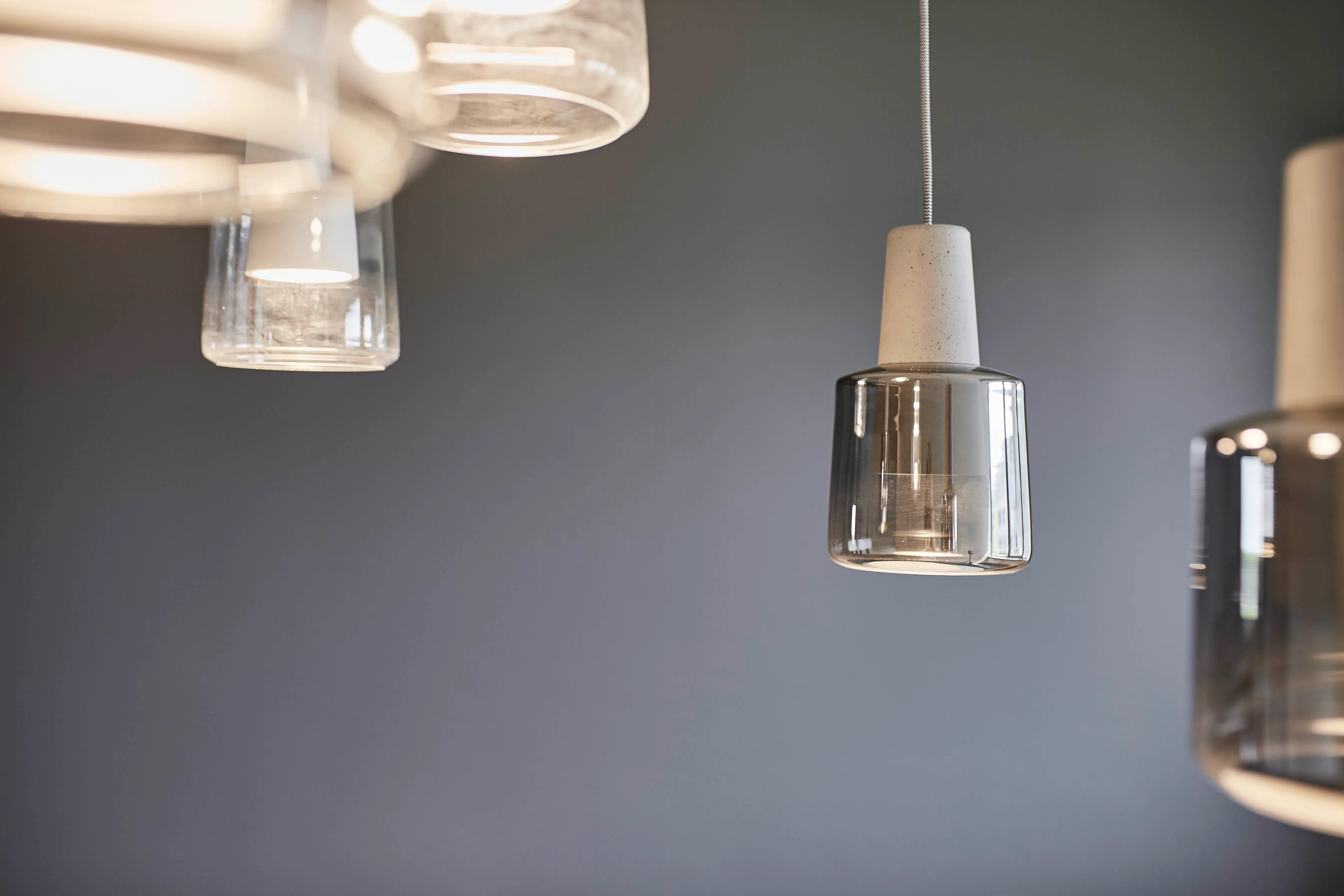 Moderne Hängeleuchte mit klarem Glasschirm und grauem Hintergrund.