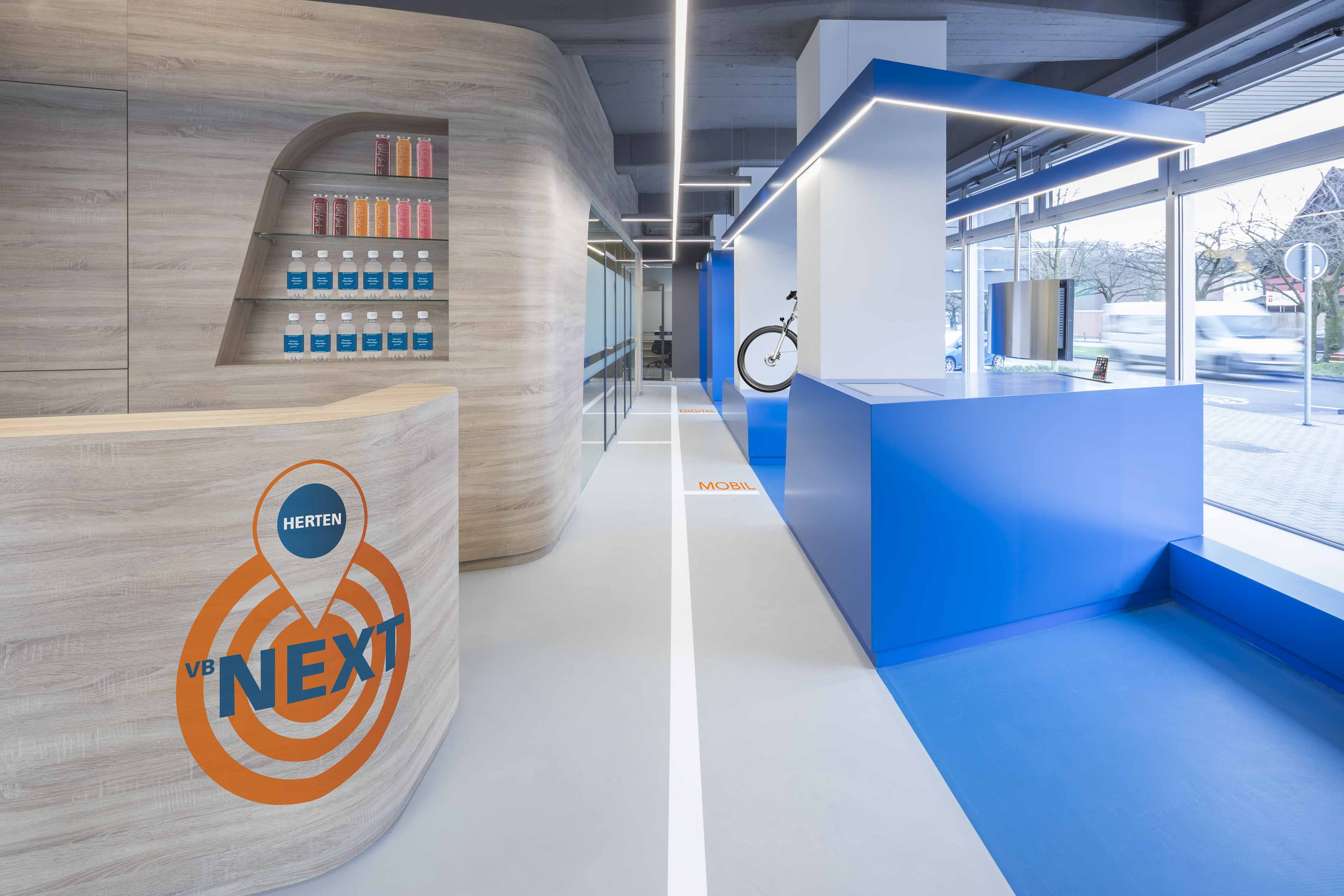 Modernes Büro mit Holztheke, blauen Möbeln und großen Fenstern mit Blick auf die Straße.