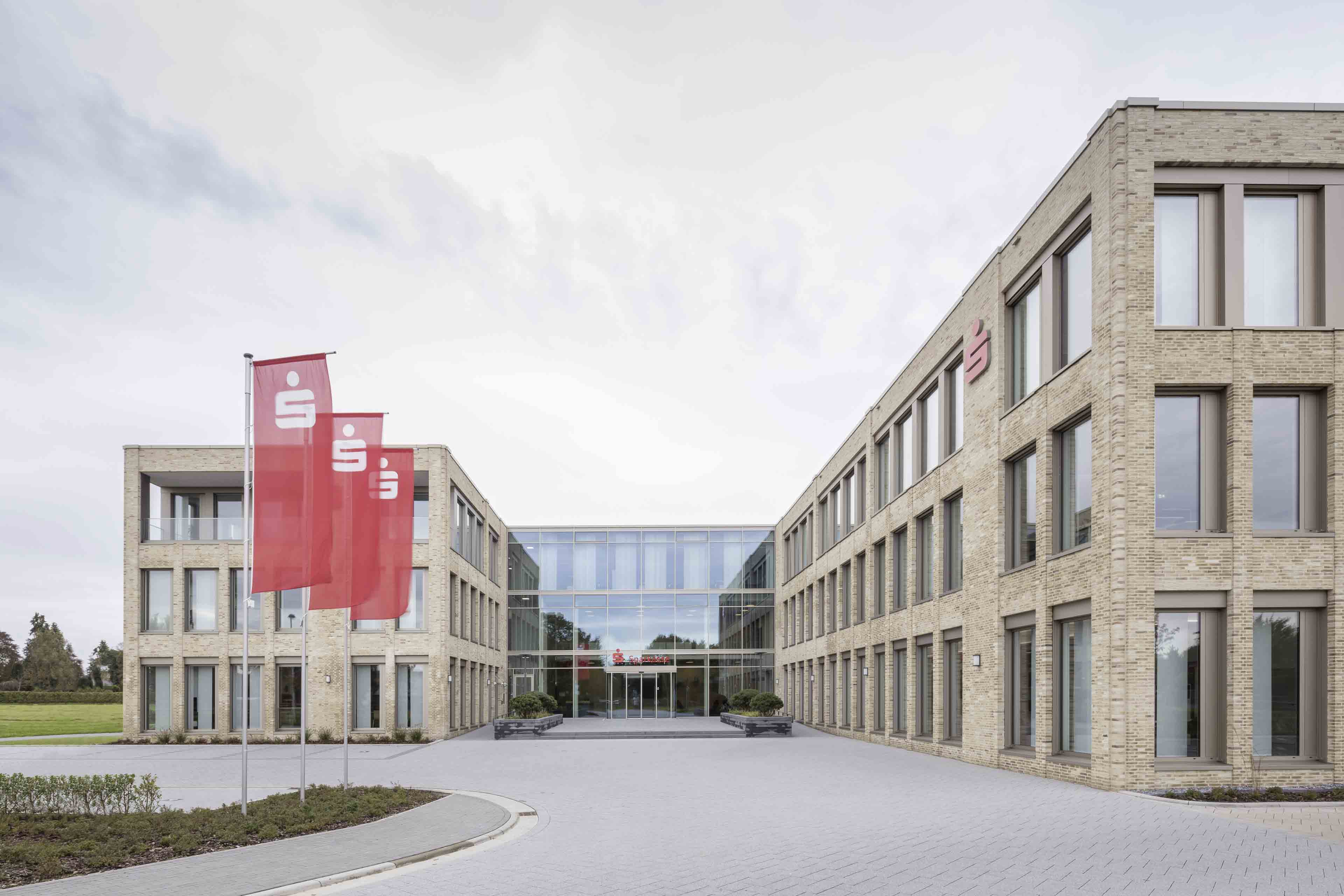 Modernes Gebäude der Sparkassenzentrale mit roten Fahnen und Logo vor dem Eingangsbereich.