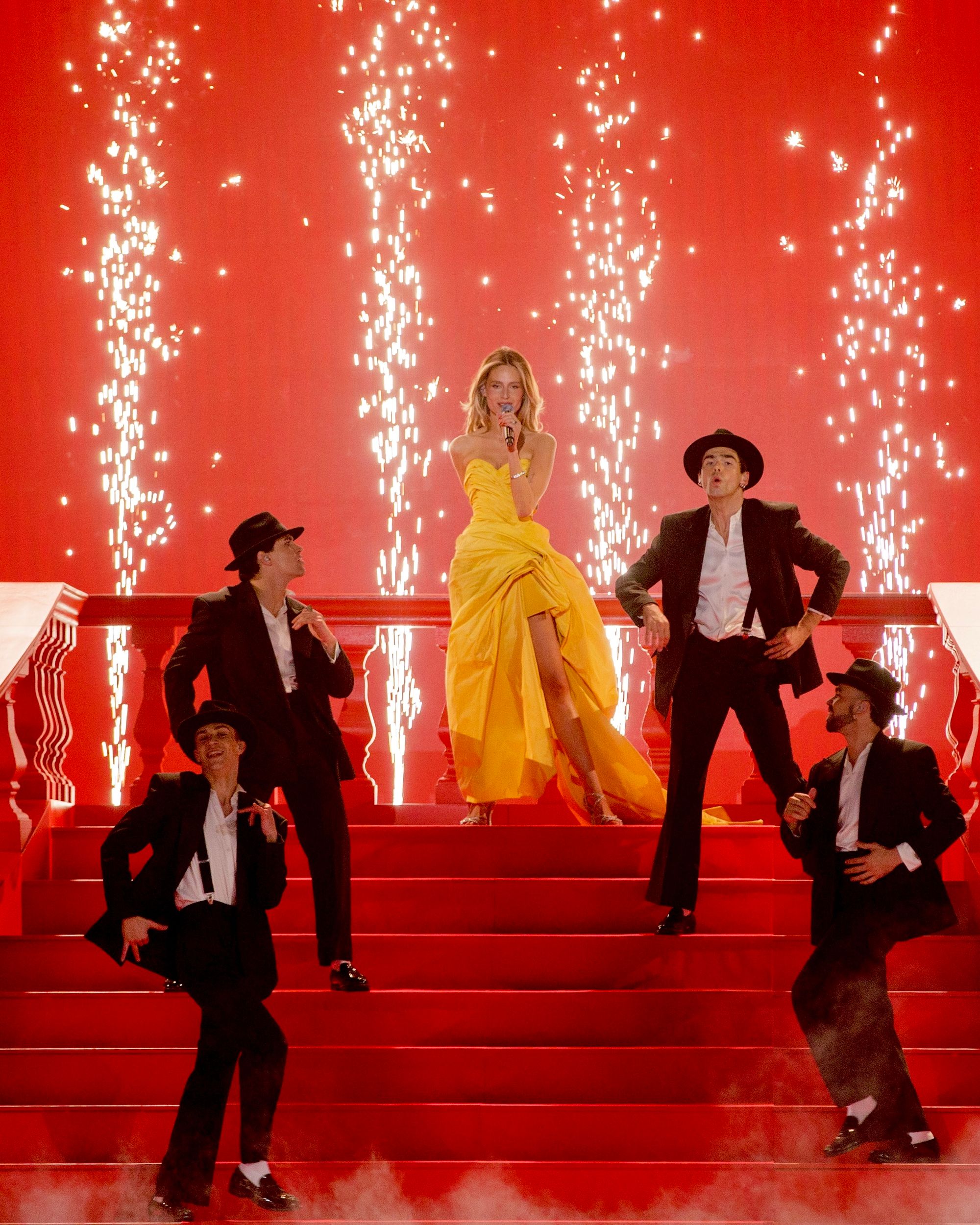 Older man wearing dark sunglasses and a navy sweater sitting at a table, holding a white gift box with a red ribbon, with text saying 'Sunnies that say "I know what I like"'.