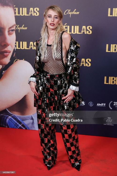 Older man wearing dark sunglasses and a navy sweater sitting at a table, holding a white gift box with a red ribbon, with text saying 'Sunnies that say "I know what I like"'.