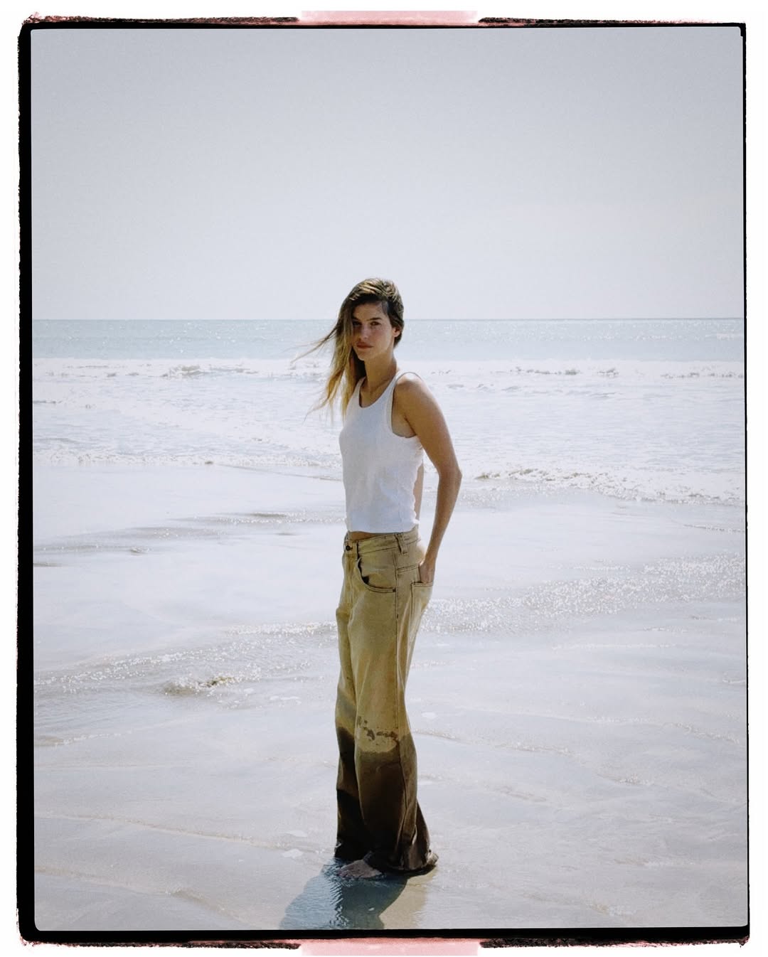 Older man wearing dark sunglasses and a navy sweater sitting at a table, holding a white gift box with a red ribbon, with text saying 'Sunnies that say "I know what I like"'.