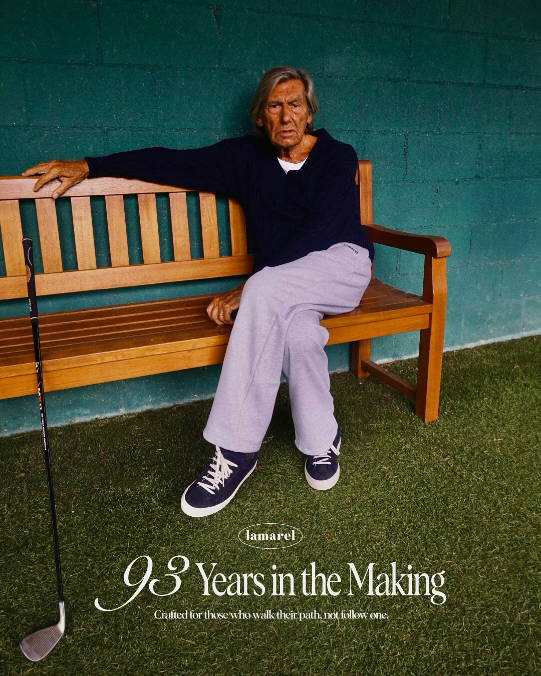 Older man wearing dark sunglasses and a navy sweater sitting at a table, holding a white gift box with a red ribbon, with text saying 'Sunnies that say "I know what I like"'.