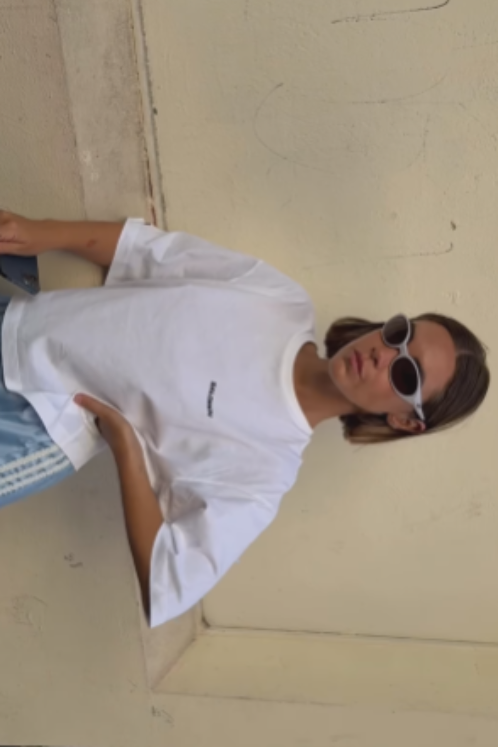 Older man wearing dark sunglasses and a navy sweater sitting at a table, holding a white gift box with a red ribbon, with text saying 'Sunnies that say "I know what I like"'.