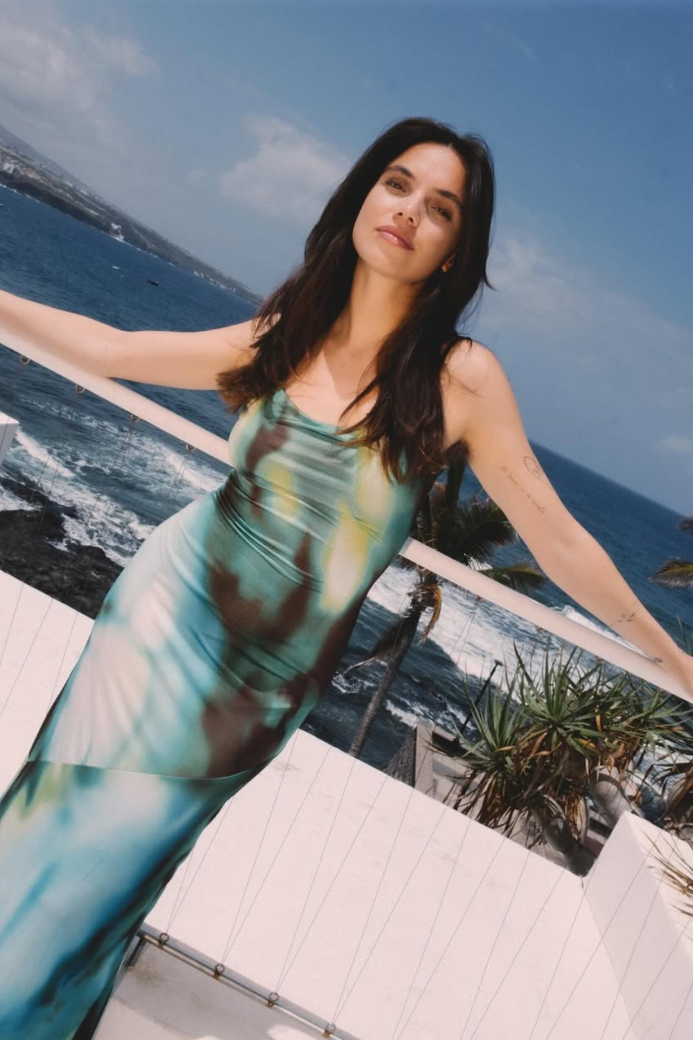 Older man wearing dark sunglasses and a navy sweater sitting at a table, holding a white gift box with a red ribbon, with text saying 'Sunnies that say "I know what I like"'.